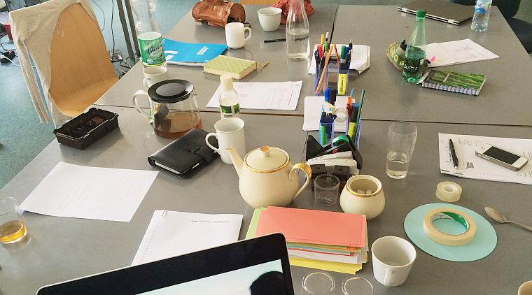 Ein Tisch mit vielen Dingen wie Notizzettel, Laptop, Kaffee und Teetassen,...